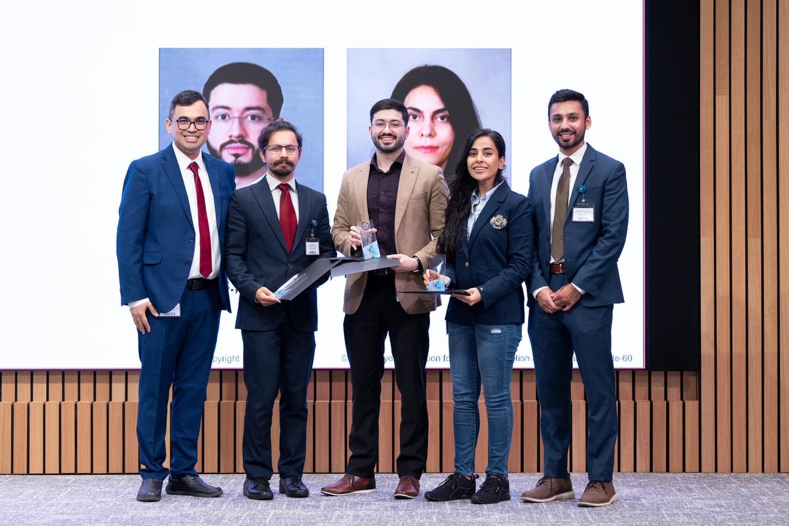 Five people on stage at the Mayo Research Fellows' Association awards, two holding award trophies.